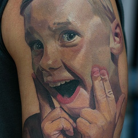 Kinderportret tattoo op de bovenarm in kleur realisme, gezet door Al Minz in Inksane tattoo en piercing.