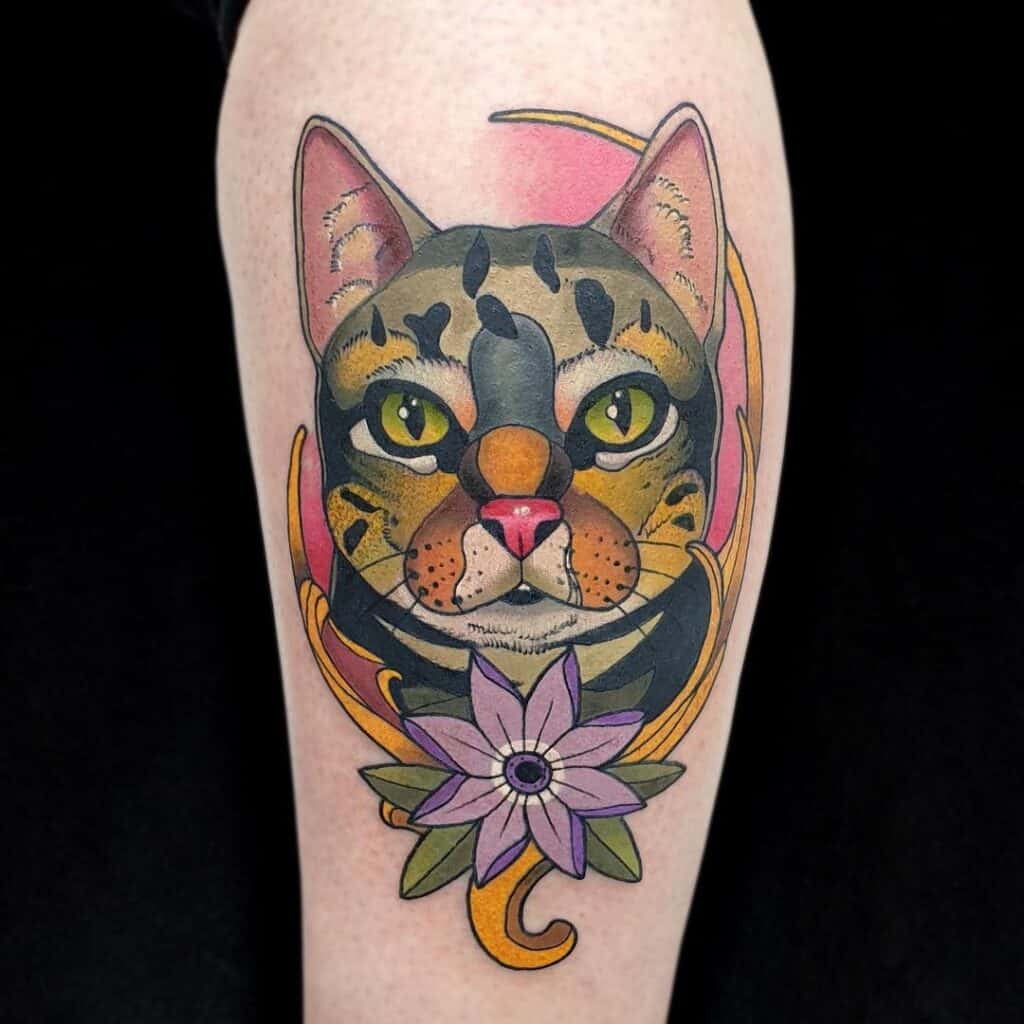 Neo-traditional tattoo van een kat met omlijsting en bloemen. Full color