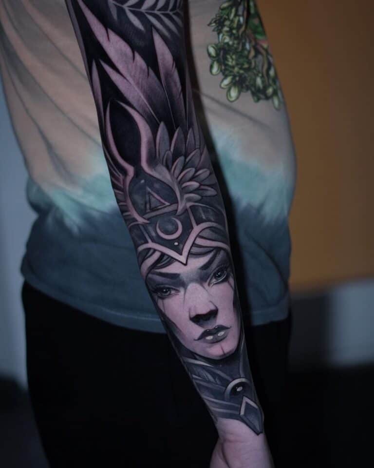 Black and grey tattoo op de onderarm, vrouwengezicht met helm en velugels
