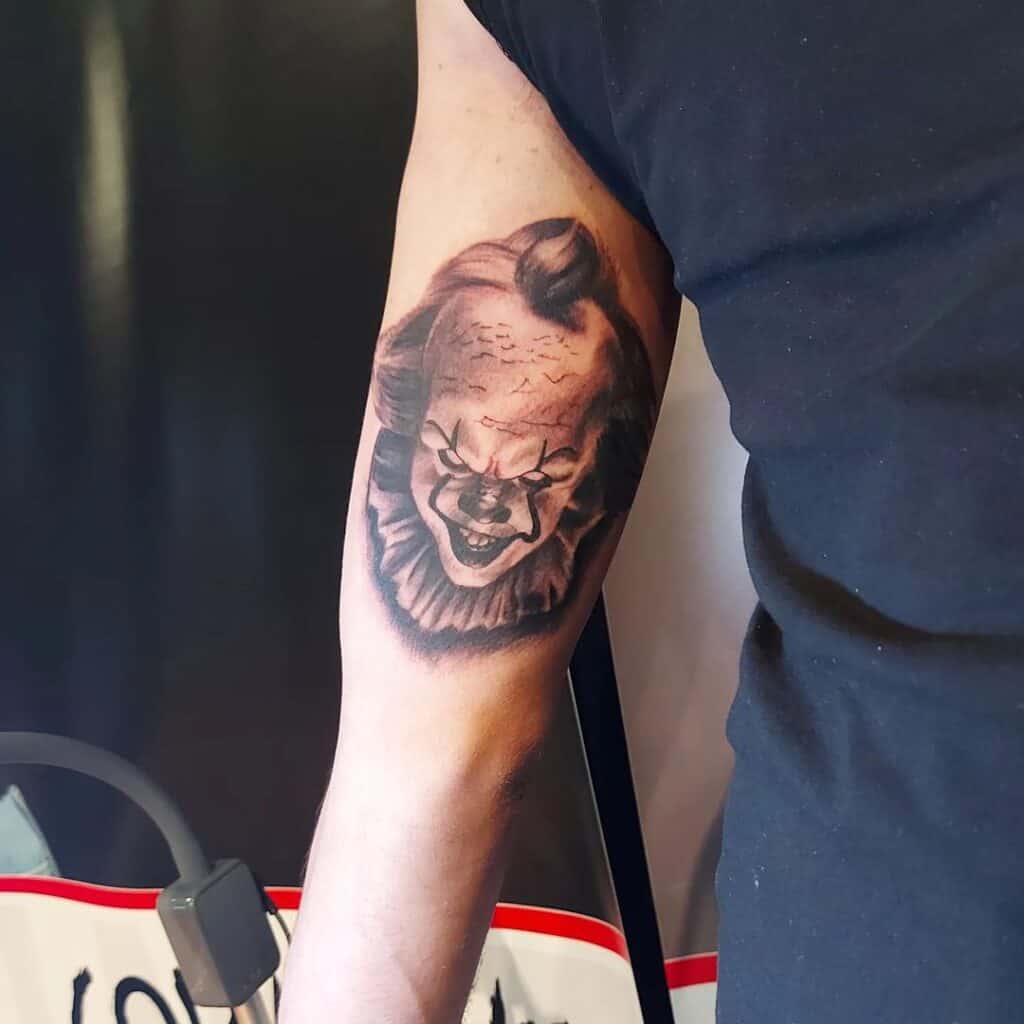 Black and grey tattoo op de binnenkant van een bovenarm, portret van Pennywise