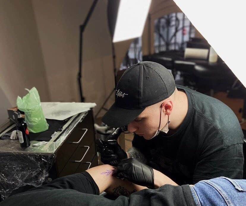 Foto van Steven, vaste artiest bij Inksane Brussel, die een tattoo plaatst op de arm van zijn klant