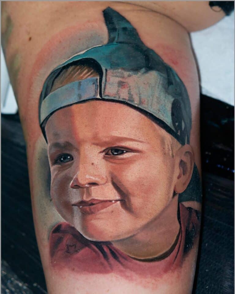 Tattoo in kleur realisme op binnenkant bovenarm. Kleine jongen met pet. Gezet door Al Minz bij Inksane tattoo en piercing.