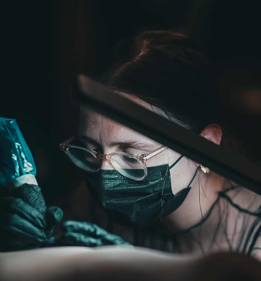 Foto van Eleni, vaste artieste bij Inksane Roeselare, die een tattoo plaatst op haar klant.