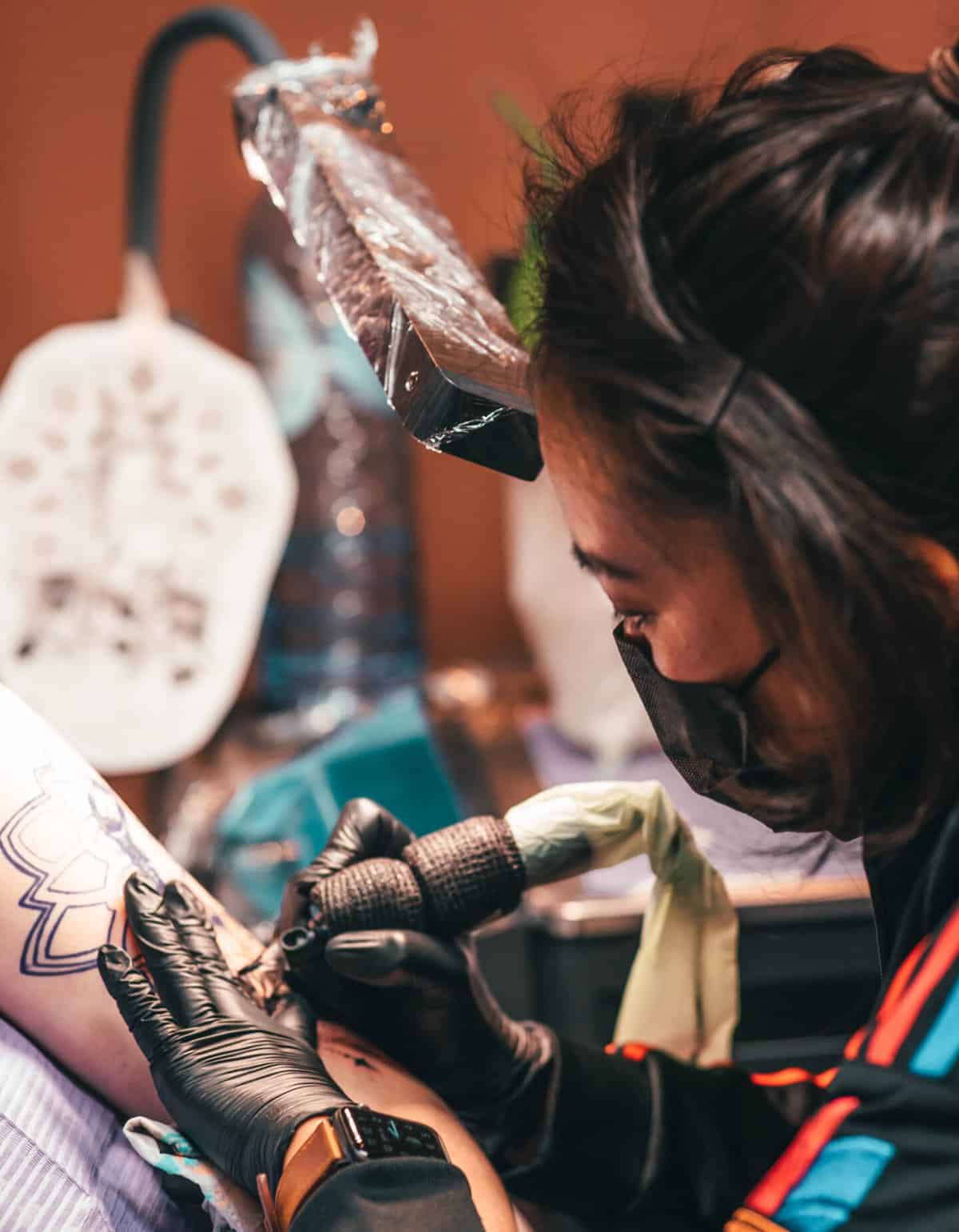 Foto van Sai die een tattoo plaatst op de bovenarm van haar klant.
