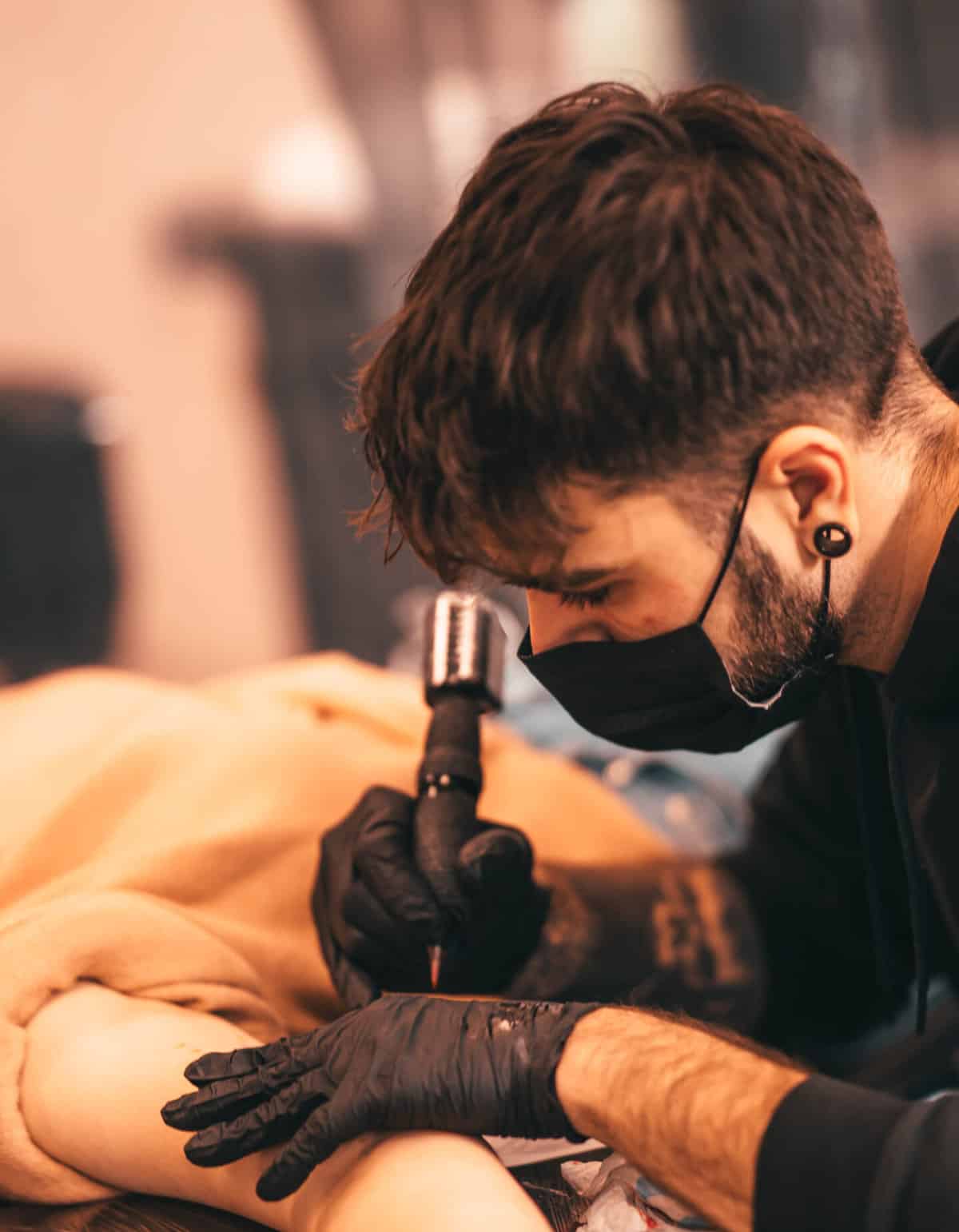 Foto van Chesney die een tattoo plaatst op de arm van zijn klant