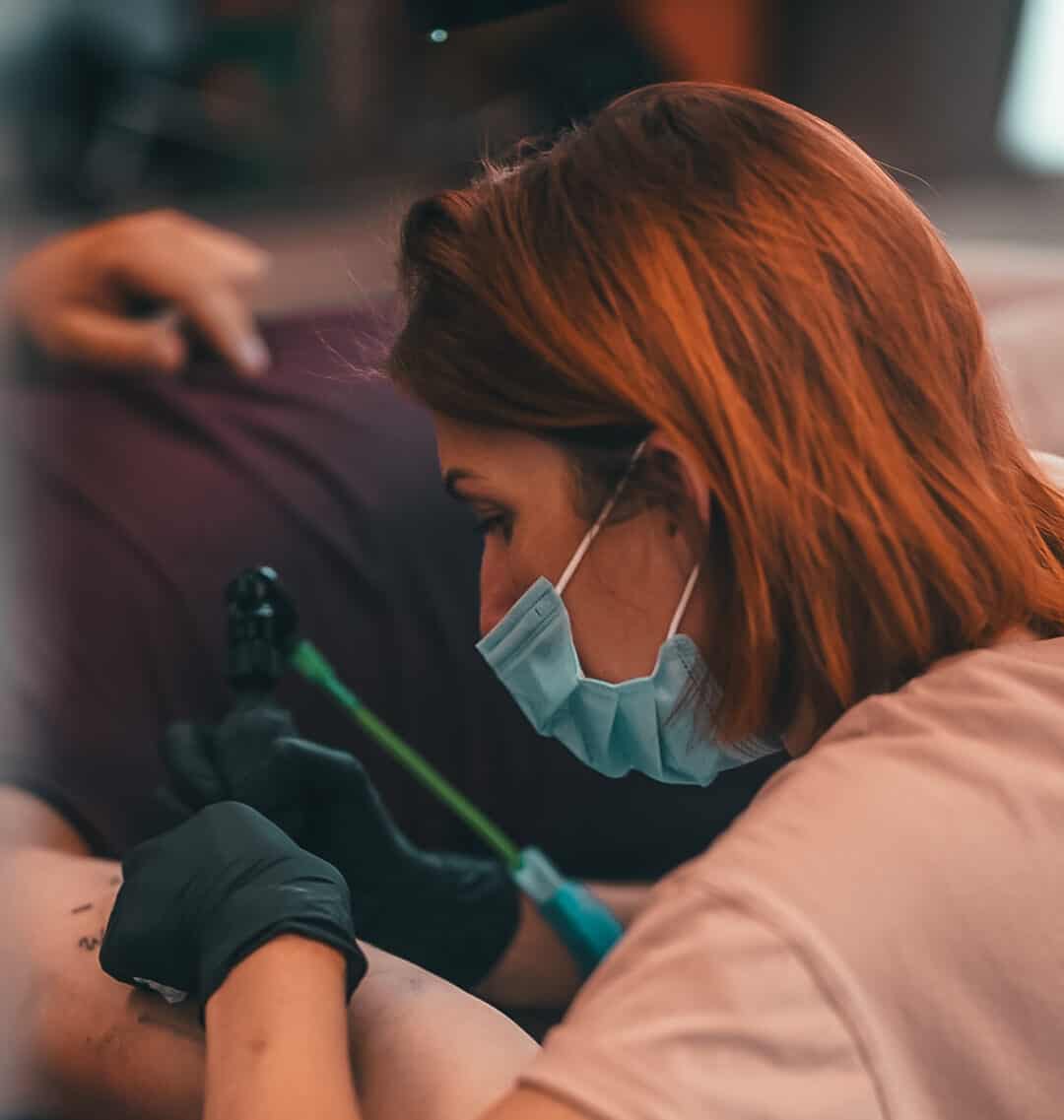 Foto van Kimberly die een tattoo plaatst op de arm van haar klant.