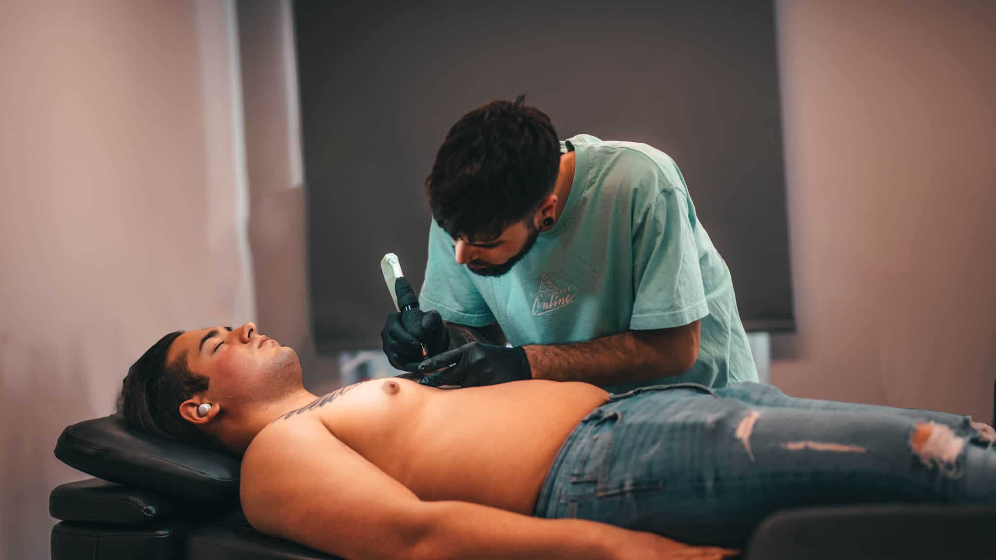 Chesney, resident artist bij Inksane Roeselare, plaatst een tattoo op de borst van een klant