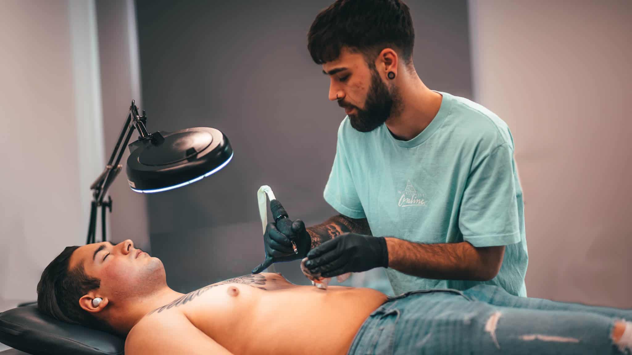 Tattoo artiest Chesney aan het werk op zijn klant zijn borstkas