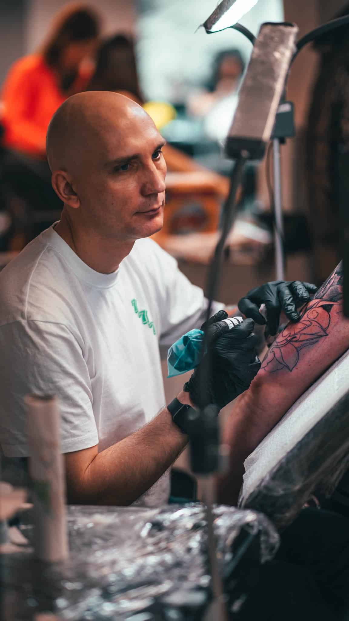 Gennadiy, gastartiest bij Inksane, plaatst een tattoo op de bovenarm van een klant.