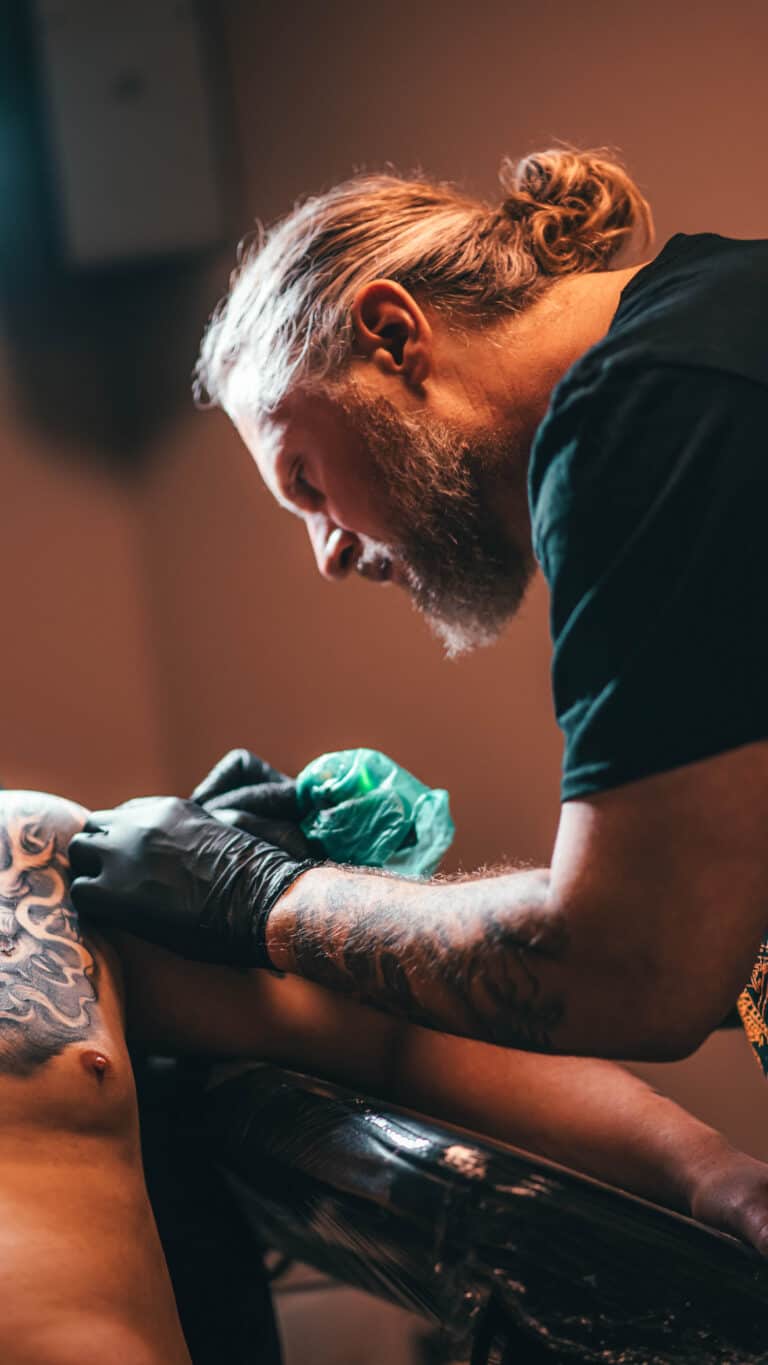 Jura Bedic, gastartiest bij Inksane Roeselare, plaatst een tattoo op de bovenarm van een klant.