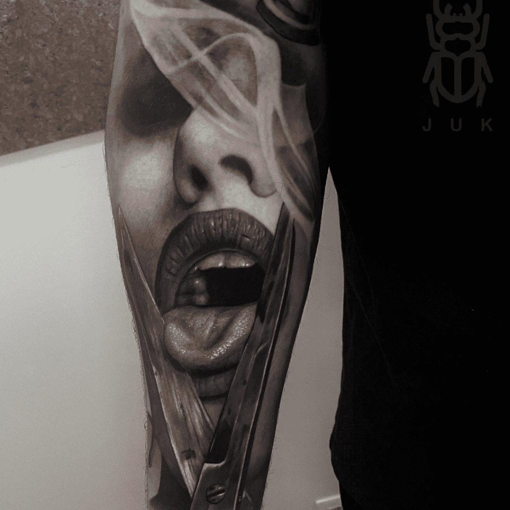 Black and grey tattoo op onderarm gezet bij Inksane tattoo en piercing. Vrouwengezicht met tong en schaar en rook.