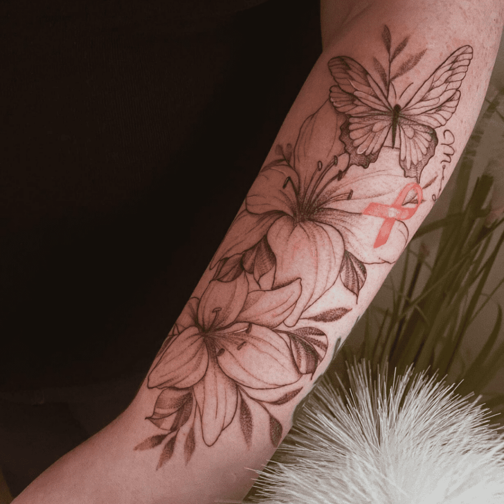 Fineline tattoo op bovenarm met bloemen, vlinder en rode think pink strik. Gezet bij Inksane tattoo en piercing