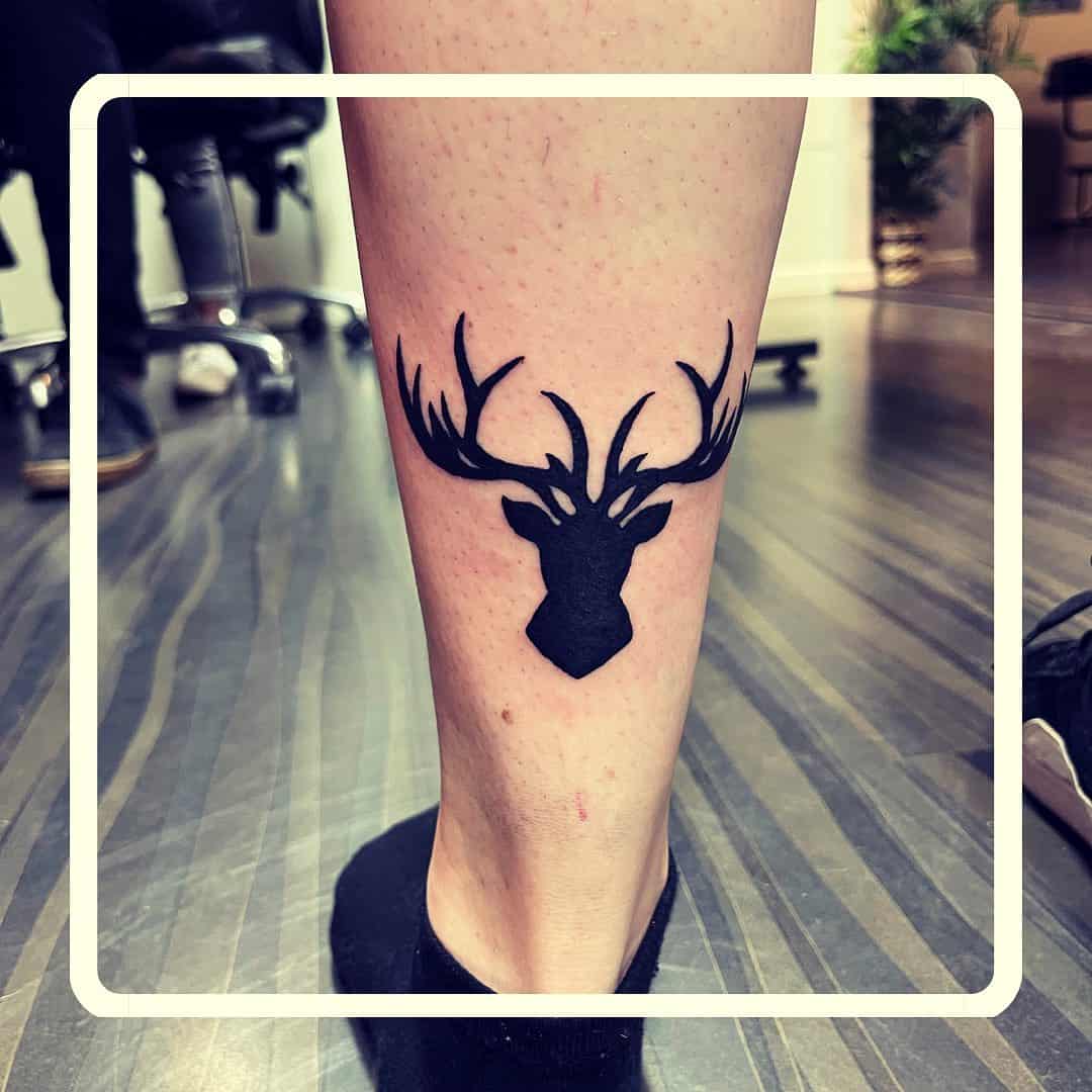 Kleine silhouet tattoo van een hert op de kuit