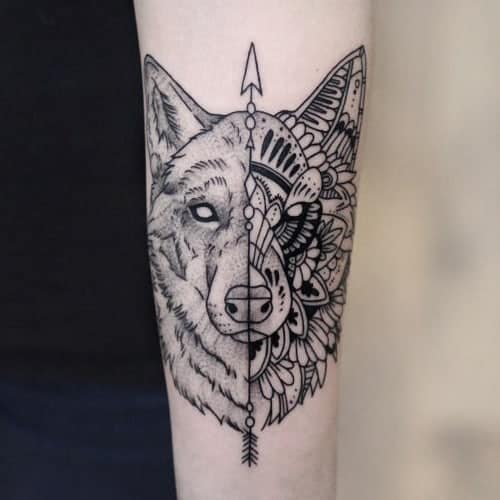 Tattoo van een wolf op een onderarm. De ene helft is een tekening, de andere helft is met mandala elementen. Geplaatst bij Inksane tattoo en piercing.