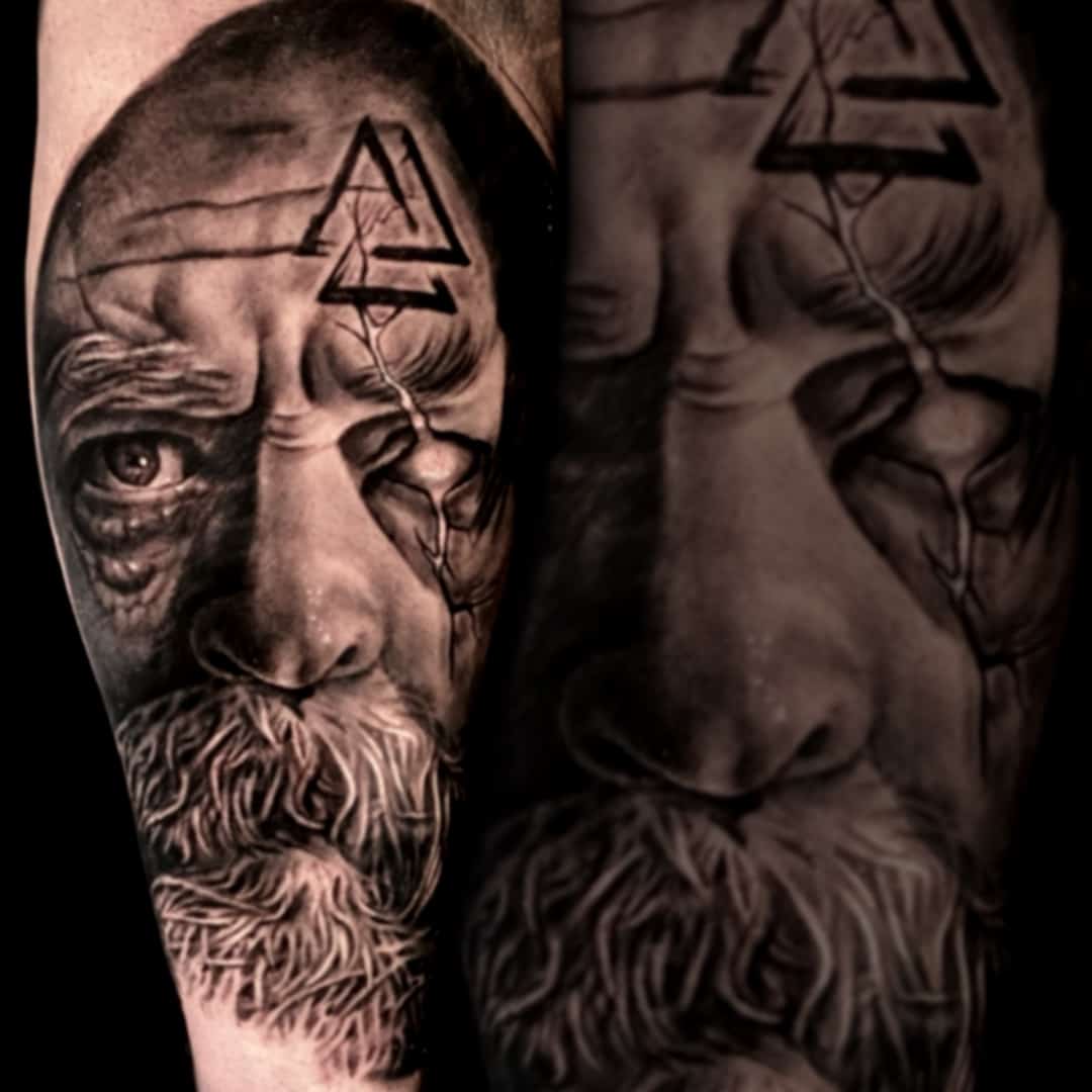 Black and grey realisme tattoo op een onderarm. Oude man met snor en baard, met runeteken op voorhoofd
